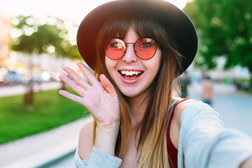 Young smiling teen happy woman making selfie on the street Smiling girl talking on video chat mobile phone app or taking selfie photo for social media. Carefree and happy, sunny spring mood. 