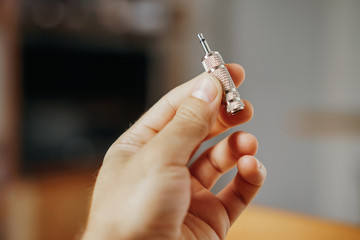 Steel metal mini jack plug stereo in the hand of the man on the background of the interior. Musical...