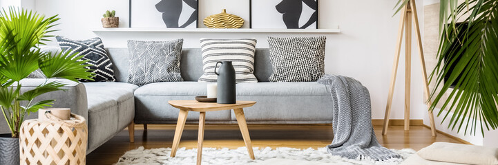 Real photo of black jug and white candle placed on small wooden table standing on fluffy carpet in...