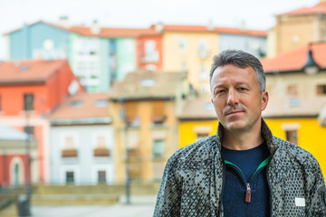 Handsome middle-aged man walking autumn street. Urban male portrait, image toned and noise added....