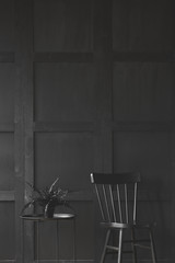 Black chair next to table with plant in monochromatic room interior. Real photo