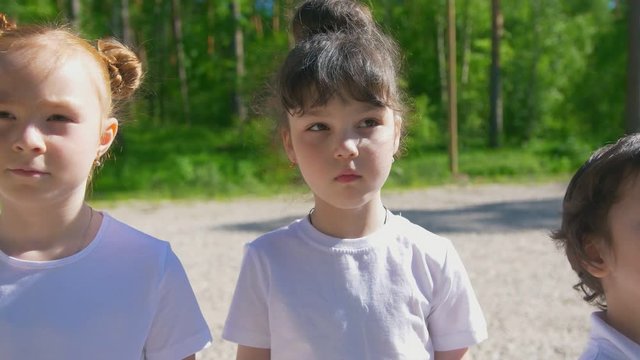 Team Of Little Caucasian Children Different Ages Lined Up In Line In At Sunny Day Outdoors