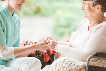 Nurse preparing a disabled pensioner for a walk in the garden of the retirement home