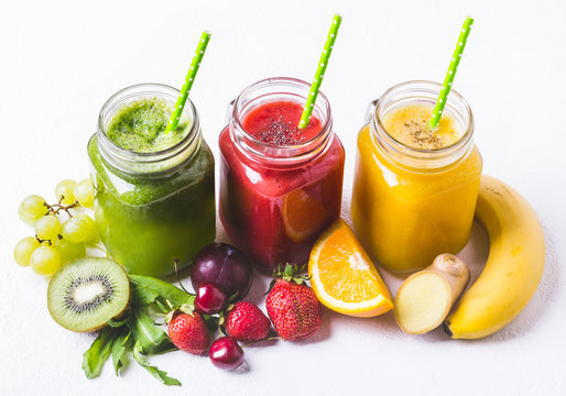 Red, yellow and green smoothie in a glass jar and ingredients on white background
