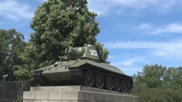 A T34 tank with green trees around it and blue sky, Berlin, Germany