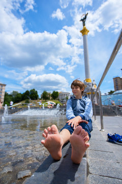 Cute boy resting near fountain on Khreshchatyk square, Kyiv, Ukraine.
