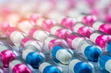Closeup pink-white and blue-white antibiotics capsule pills in blister pack. Antimicrobial drug...