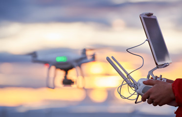drone quadcopter with digital camera flying at sunset