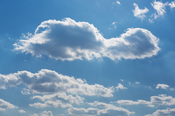 many large clouds in the backlight, stretching into the distance in perspective, against the blue...