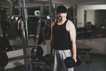 Fototapeta na wymiar Young and strong man using dumbbells at the gym. Toned image