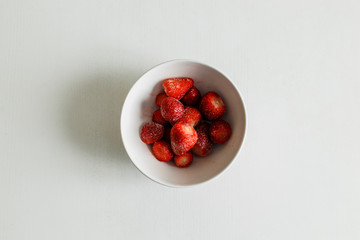 frozen strawberries lie on a white plate on a white table