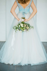 Fototapeta na wymiar Bride in a blue dress is holding flowers in her hands