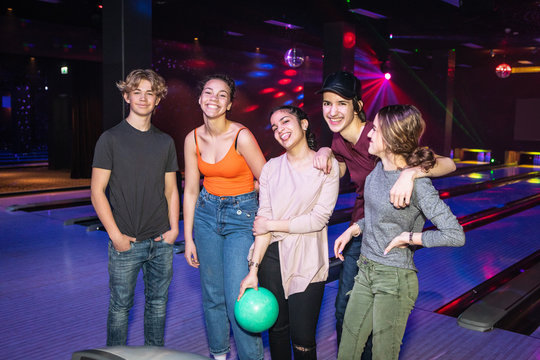 Portrait of smiling multi-ethnic teenagers standing on parquet floor at bowling alley