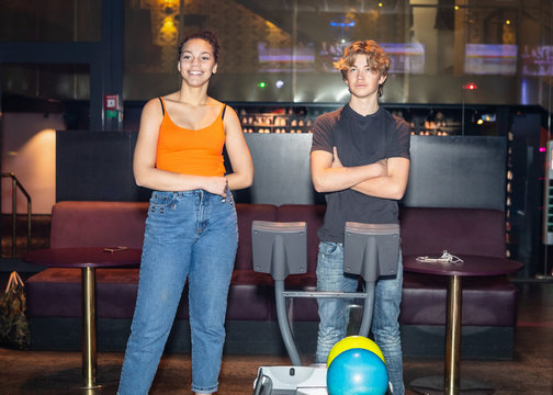 Multi-ethnic friends standing by computer at bowling alley