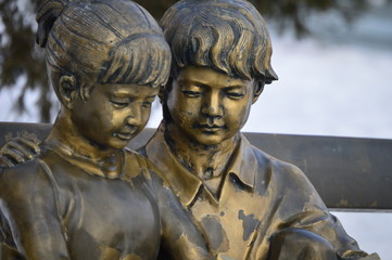 Boy and girl with the book , read and sit on the bench.