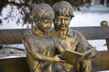 Fototapeta na wymiar Boy and girl with the book , read and sit on the bench.