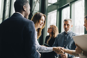 Mature businesswoman greeting colleagues in meeting at office