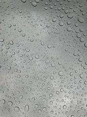 Rain drops on window glasses surface with cloudy background Natural Pattern of raindrops isolated on cloudy background 