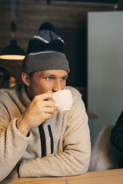 Thoughtful mid adult man having coffee at table in log cabin