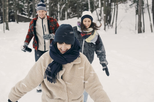 Cheerful friends walking on snow covered field