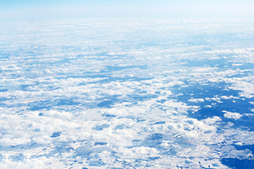 View from the top of the plane on clouds and snow-covered fields