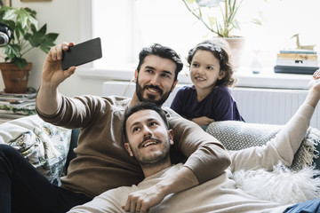 Two men and girl taking selfie at home