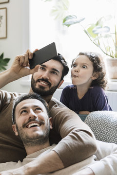 Two men and girl taking selfies at home