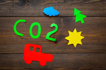 Car pollutes the environment by carbon dioxide. Car, environment and CO2 cutout on dark wooden...