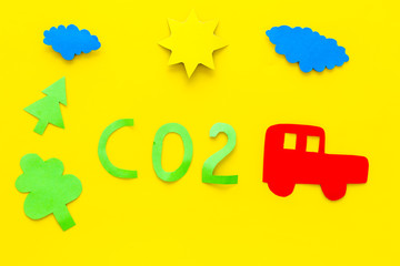 Car pollutes the environment by carbon dioxide. Car, environment and CO2 cutout on yellow background top view