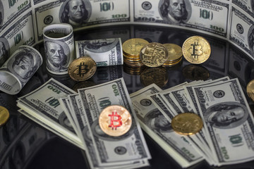 Fototapeta premium Bitcoins btc bit-coin stand on a black reflective background. One hundred dollar American bills. Crypto currency in cyberspace as a system of payment.