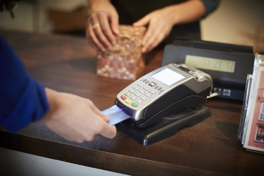 Cropped image of customer paying through credit card at checkout counter