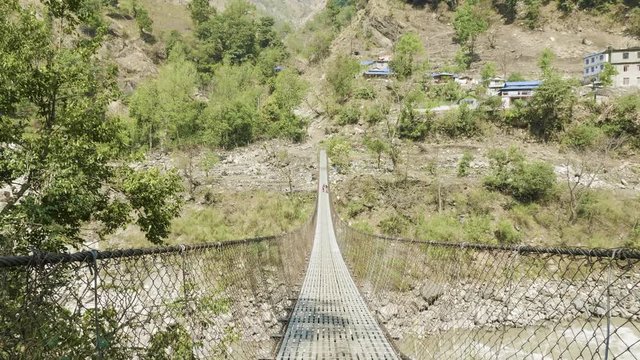Local kids run and play on the suspension bridge over the river in Nepal.