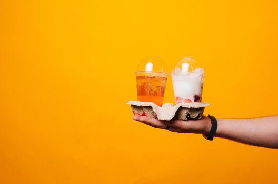 Man holding Take-away fresh lemonade and ice cream over yellow background