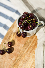  Delicious burgundy large cherry in an aluminum mug on the table. Still-life in the rustic style