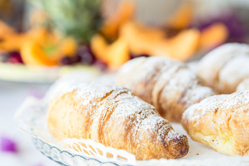 Croissants on a glass tray. Close-up of a croissant with icing sugar. Breakfast