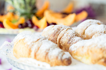 Croissants on a glass tray. Close-up of a croissant with icing sugar. Breakfast