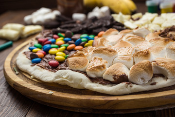 sweet pizza with chocolate and marshmallow on wooden background