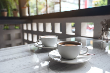 Closeup image of two white cups of hot coffee on table in cafe