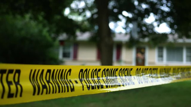 Caution tape for a police investigation near residential home as seen from front yard - V1