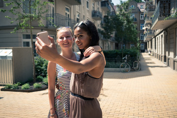Freundinnen machen Selfi vor Wohnhaus