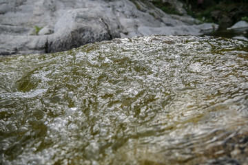 Pure mountain water flowing over mineral stones and rocks, refreshing and calming nature atmosphere with water flow, natural water detail and close up