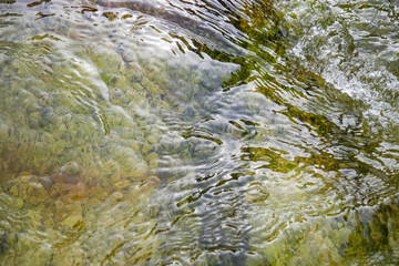 Pure mountain water flowing over mineral stones and rocks, refreshing and calming nature atmosphere with water flow, natural water detail and close up
