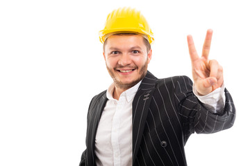 Business man in safety yellow helmet showing victory gesture.