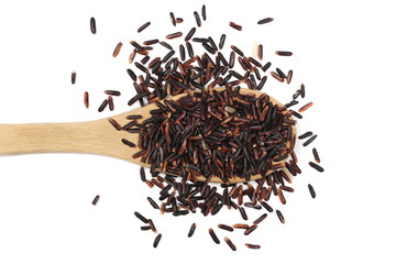 Organic black rice in wooden spoon isolated on white background, top view