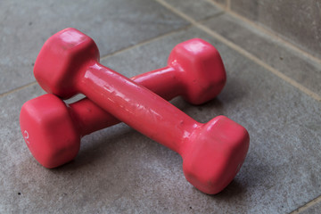 Two pink dumbbells lie cross on the cross. Healthy lifestyle, sport.
