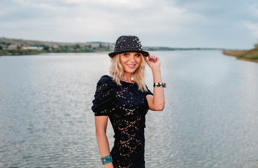 Obraz premium girl in black dress and hat in front of river