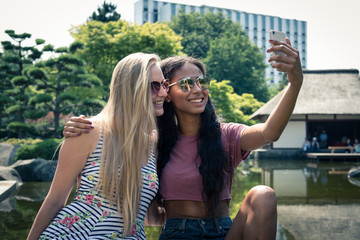 Fototapeta premium Freundinnen machen Selfi im Park am Teich