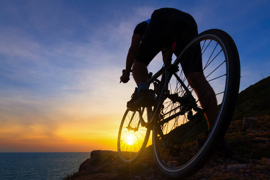 Asian man riding bicycle on rocky trail at sunset.relaxing concept.