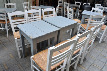 Wooden table and chair in cafe, summer terrace. Old grey wooden vintage tables and chairs with straw seat in Cyprus. Interior of summer cafe.