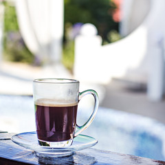 A cup of espresso and a pool in the background. Morning coffee. Summer Breakfast.